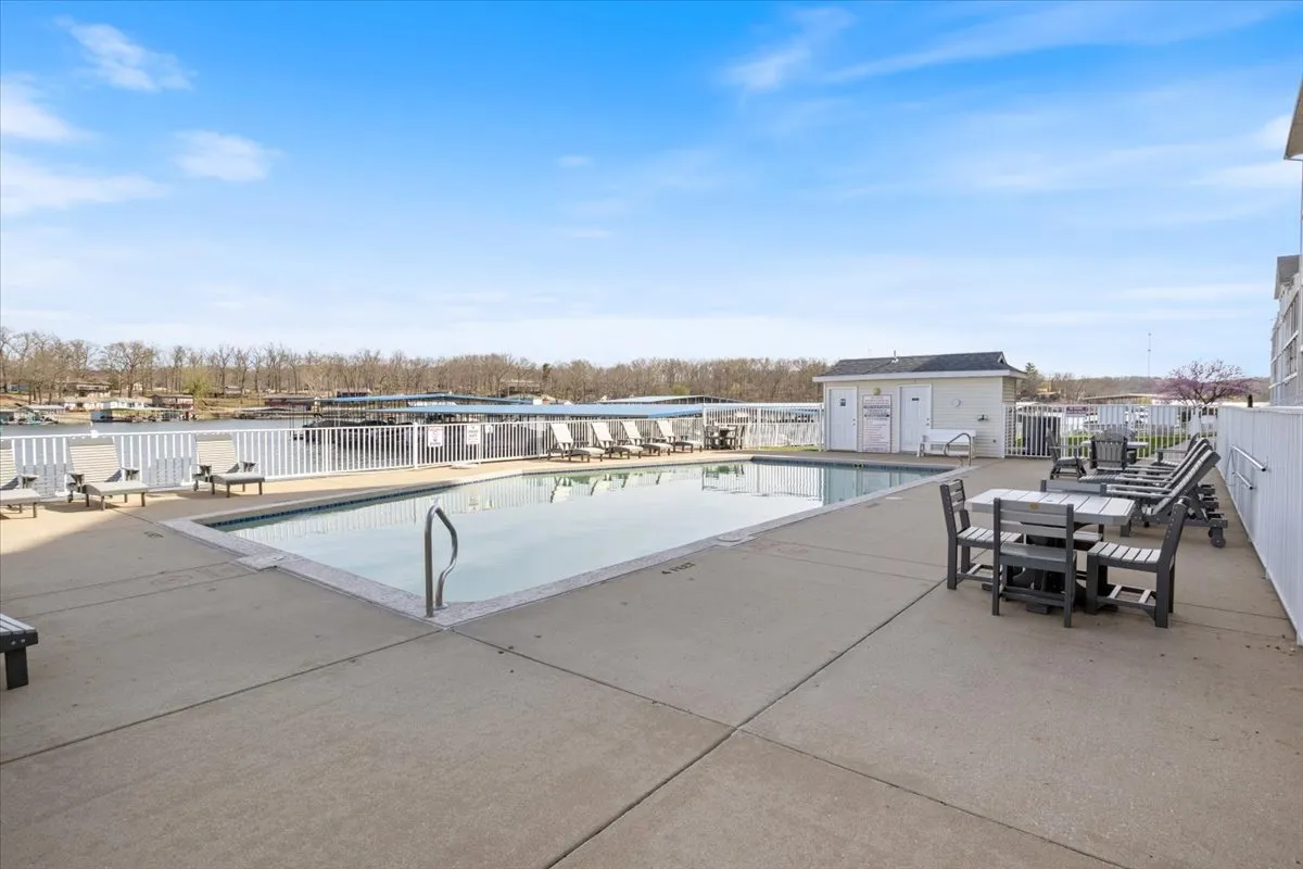 An inviting exterior scene with a swimming pool, outdoor seating, and sweeping waterfront views. The space is ideal for sunbathing, pool parties, or quiet gatherings by the water.