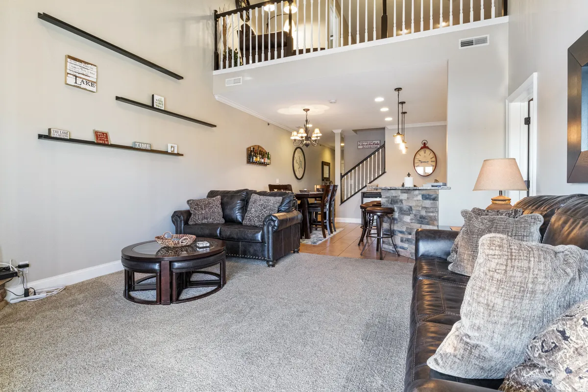 A cozy living area with a comfortable sofa, coffee table, built-in shelves, and a staircase. The space is arranged for intimate gatherings and family relaxation, suggesting a home-like comfort that is welcoming in any season.